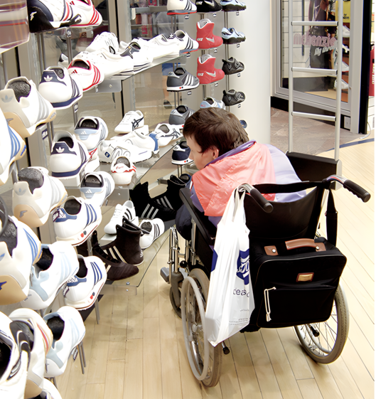 a wheelchair user is in a shop looking at a selection of trainers